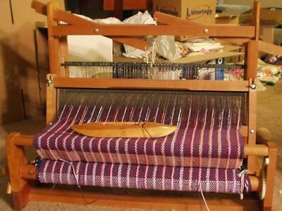 A table loom with shuttle and some cloth in the process of being woven.